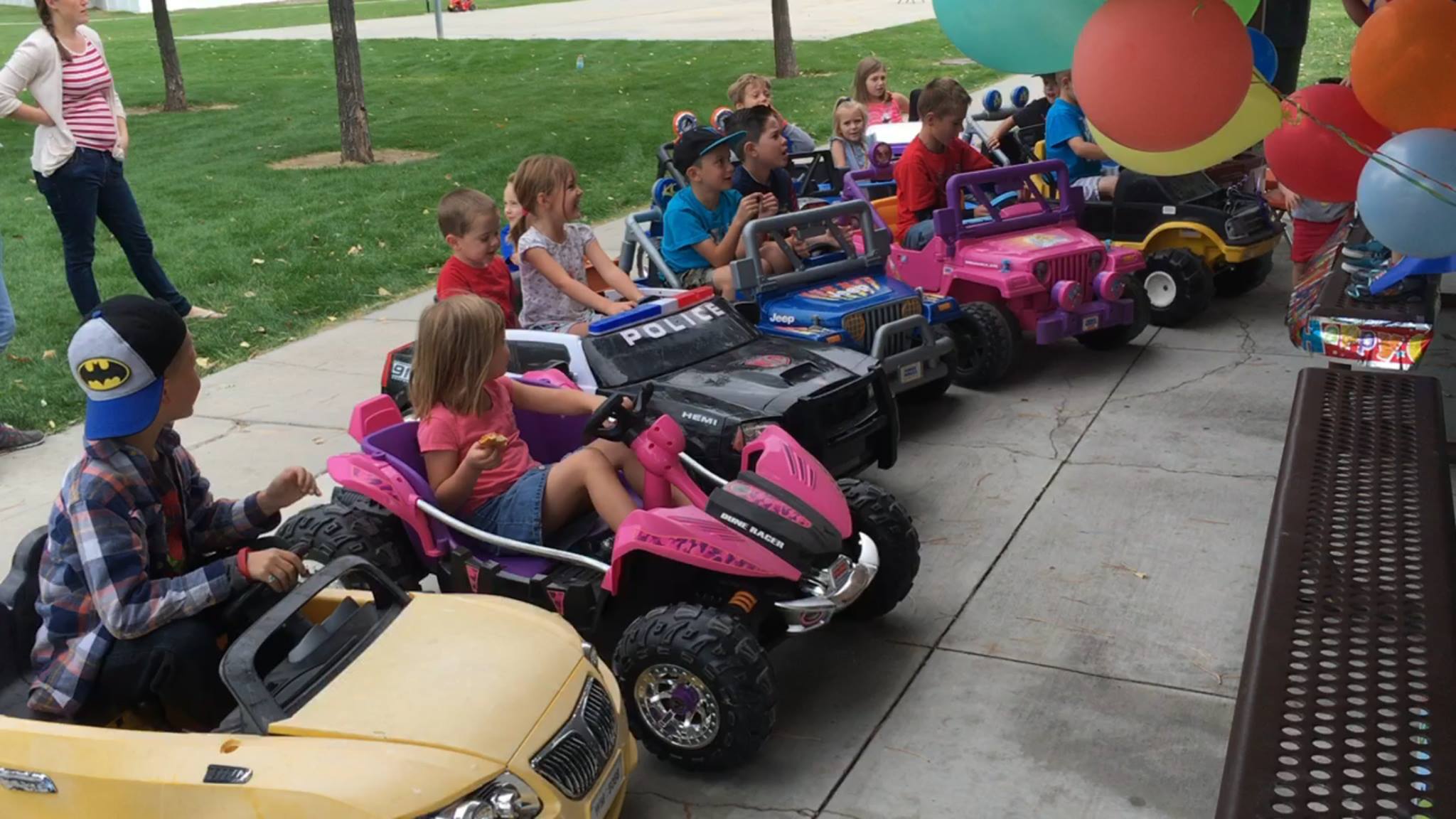 Kids lined up in Power Wheels with balloons